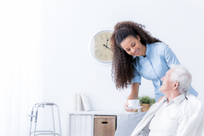 smiling nurse giving tea to elderly man